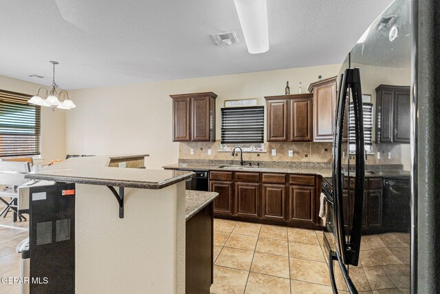 kitchen with backsplash, sink, decorative light fixtures, a chandelier, and stainless steel refrigerator