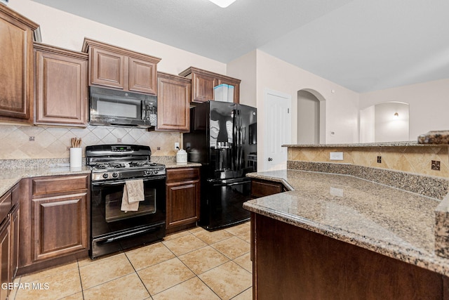 kitchen featuring tasteful backsplash, light stone counters, light tile patterned floors, and black appliances