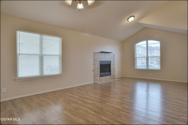 unfurnished living room featuring light hardwood / wood-style flooring, ceiling fan, lofted ceiling, and a tiled fireplace