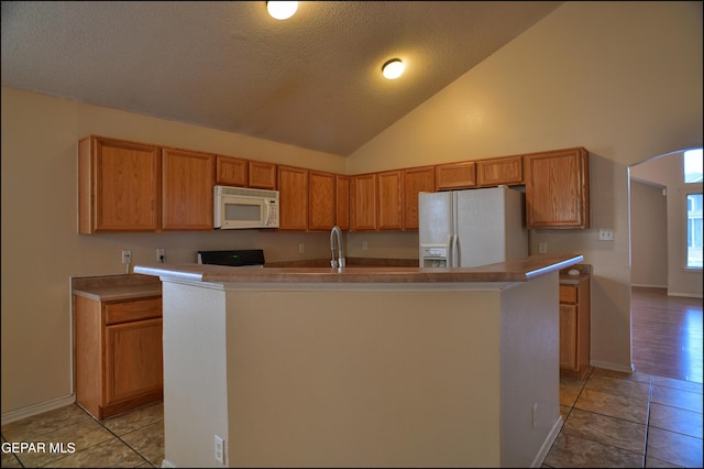 kitchen with white appliances, a textured ceiling, light tile patterned floors, a center island with sink, and high vaulted ceiling