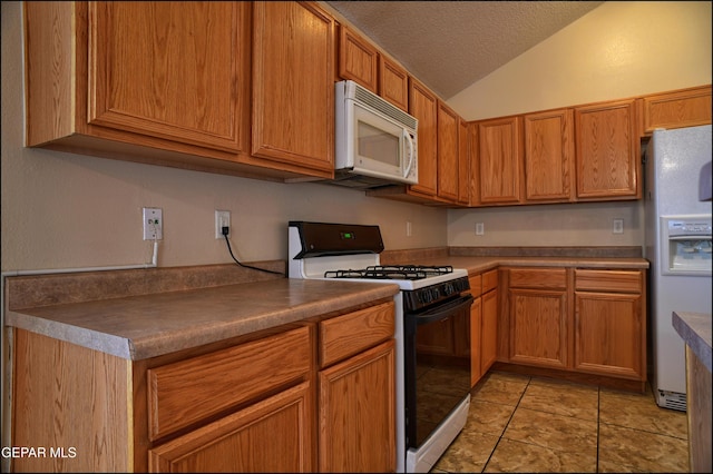 kitchen with a textured ceiling, white appliances, light tile patterned floors, and lofted ceiling