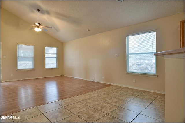 empty room with ceiling fan, plenty of natural light, light hardwood / wood-style floors, and vaulted ceiling