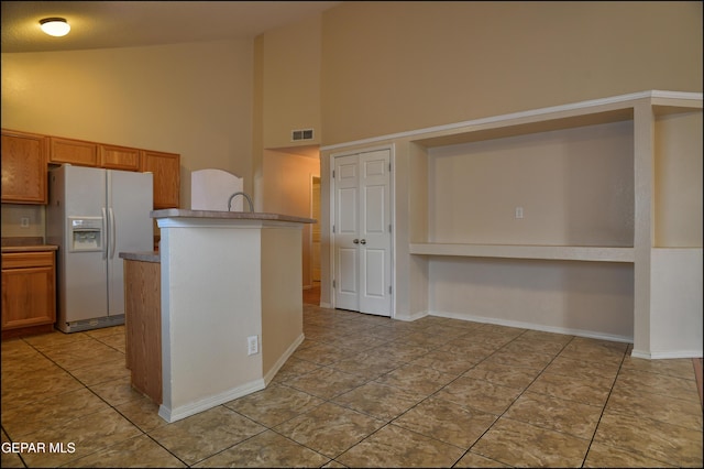 kitchen featuring light tile patterned floors, high vaulted ceiling, and white refrigerator with ice dispenser