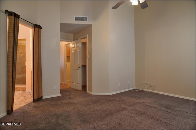 unfurnished room with a towering ceiling, carpet floors, and ceiling fan