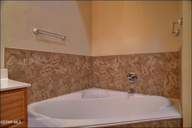 bathroom featuring vanity and tiled bath