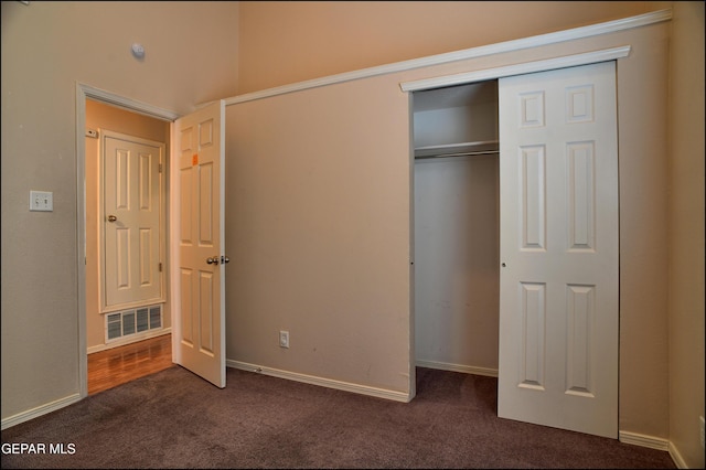 unfurnished bedroom with a closet and dark carpet