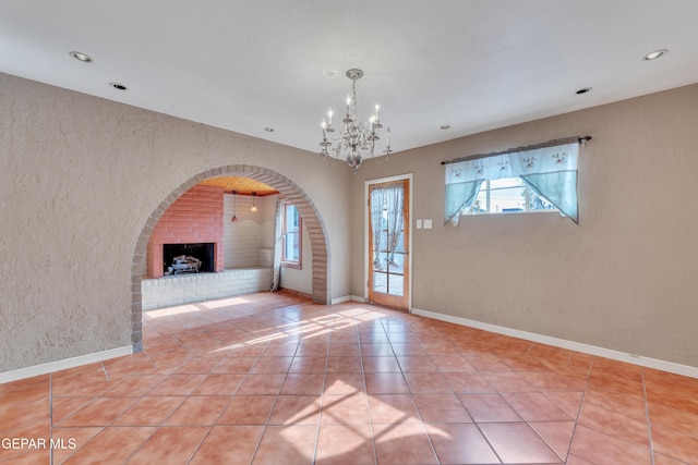 unfurnished living room with tile patterned flooring, a fireplace, and a notable chandelier