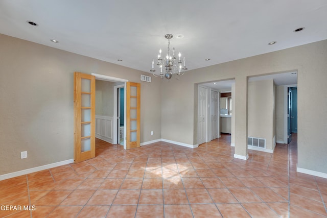 spare room with a chandelier, french doors, and light tile patterned flooring