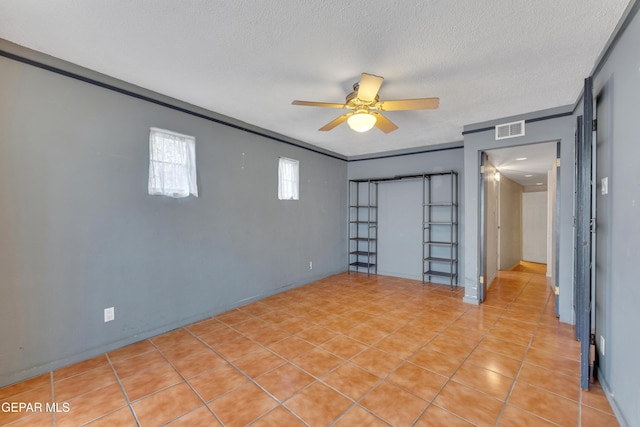 interior space with ceiling fan, light tile patterned floors, a textured ceiling, and ornamental molding