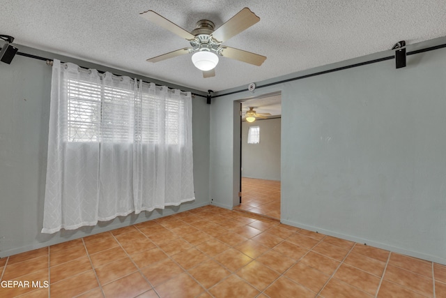 tiled spare room with ceiling fan, a barn door, and a textured ceiling