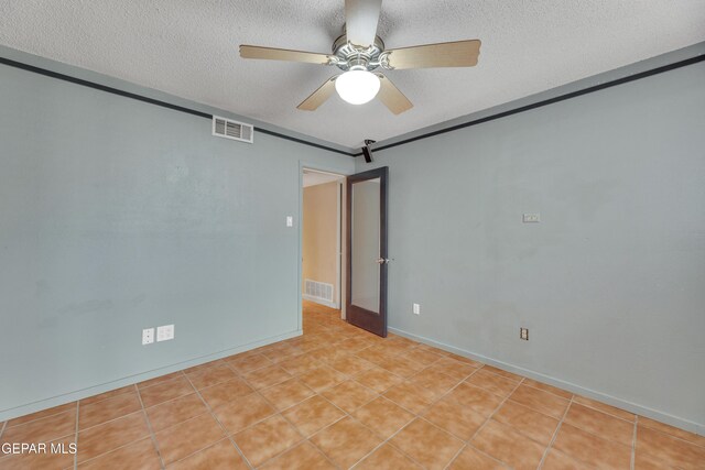 tiled empty room featuring a textured ceiling and ceiling fan