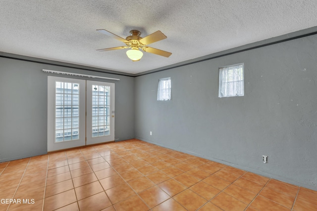 spare room featuring light tile patterned floors, a healthy amount of sunlight, and a textured ceiling