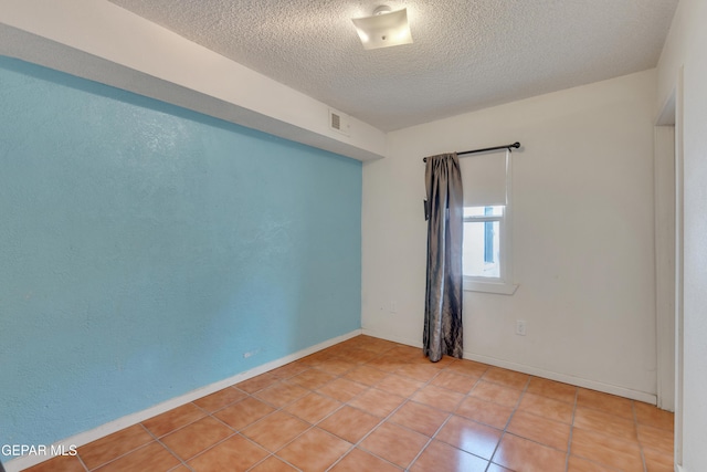 empty room featuring light tile patterned flooring and a textured ceiling