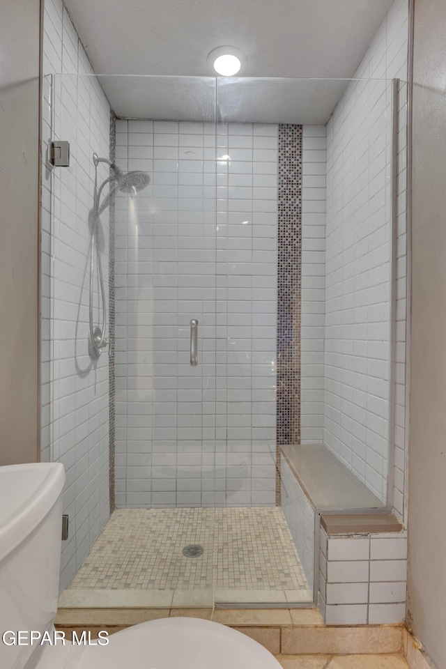 bathroom featuring toilet and a shower with door