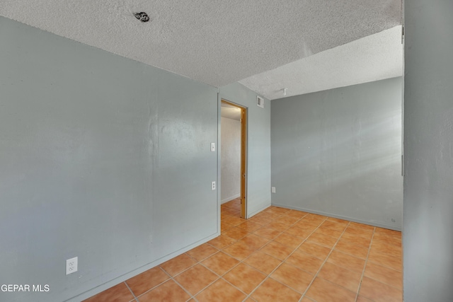 unfurnished room featuring light tile patterned flooring and a textured ceiling