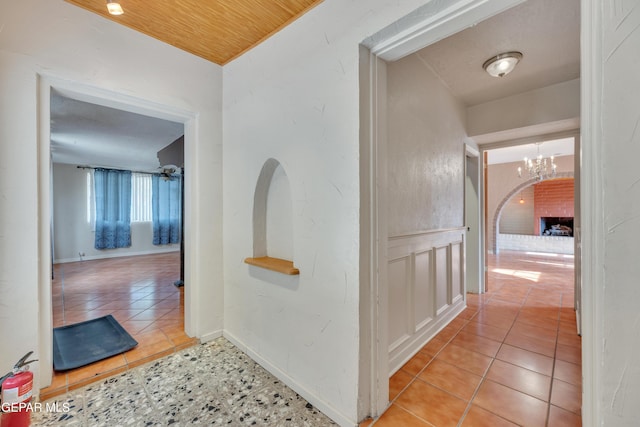 corridor featuring light tile patterned floors and a notable chandelier