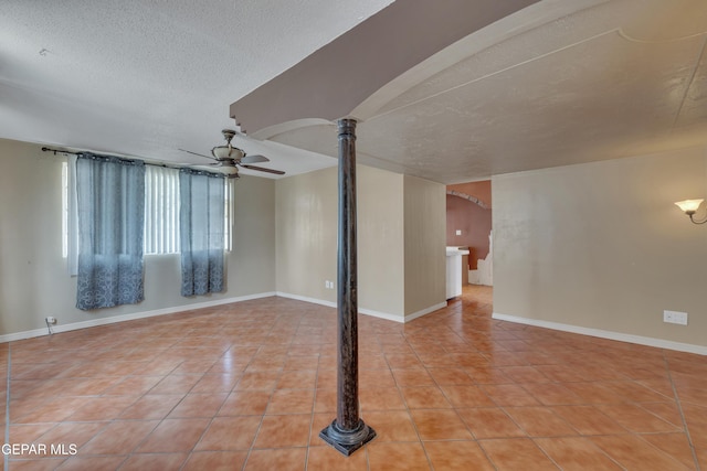 tiled empty room featuring ornate columns, ceiling fan, and a textured ceiling