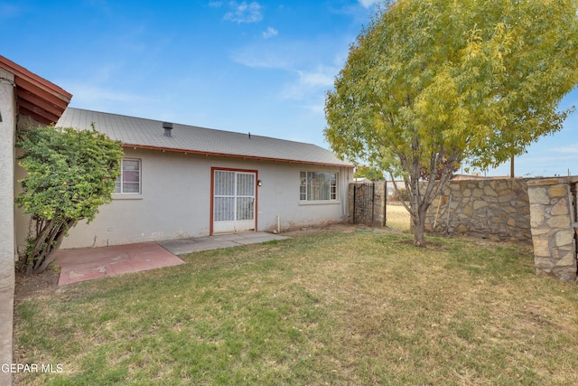 rear view of house featuring a lawn and a patio