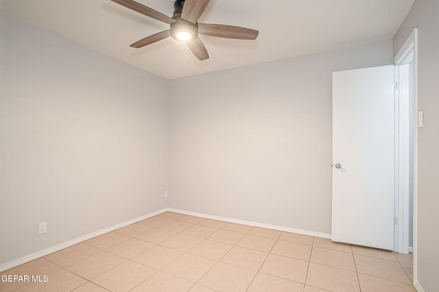 spare room with ceiling fan, light tile patterned floors, and baseboards