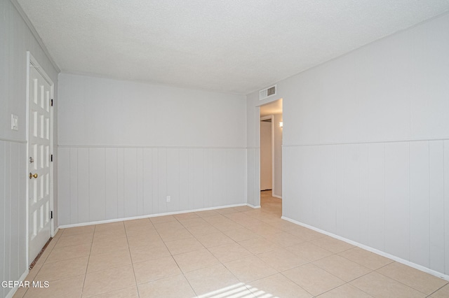 unfurnished room with visible vents, a textured ceiling, and light tile patterned flooring