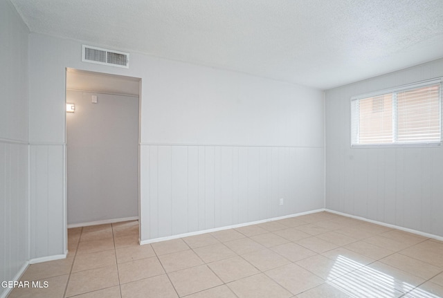 empty room featuring light tile patterned floors, visible vents, and a textured ceiling