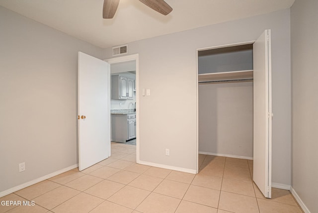 unfurnished bedroom with light tile patterned flooring, a ceiling fan, visible vents, baseboards, and a closet