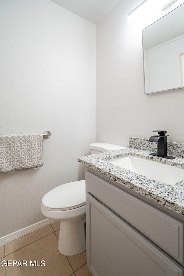 bathroom with tile patterned flooring, baseboards, vanity, and toilet