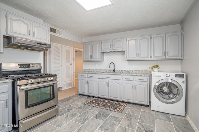 kitchen featuring stainless steel gas range oven, washer / clothes dryer, a textured ceiling, under cabinet range hood, and a sink