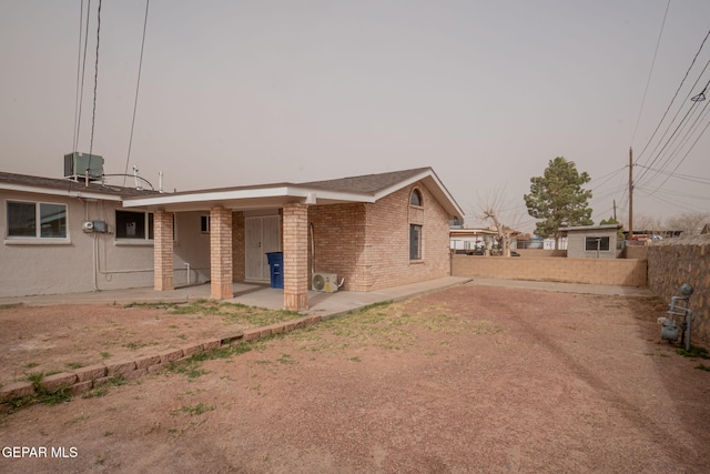 back of house featuring covered porch, central AC, brick siding, and fence