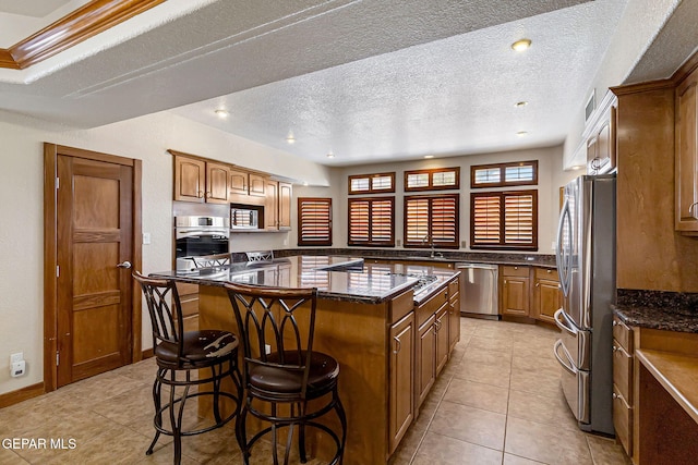 kitchen featuring a kitchen breakfast bar, a kitchen island, a textured ceiling, and appliances with stainless steel finishes