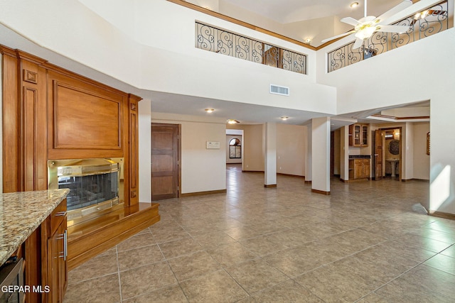 unfurnished living room with ceiling fan, a towering ceiling, and light tile patterned floors