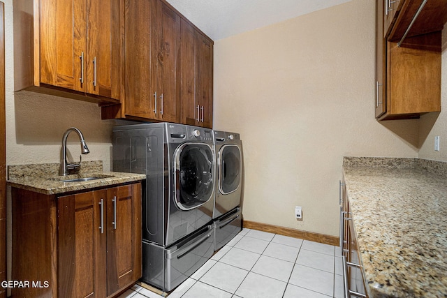 laundry area with light tile patterned flooring, washing machine and clothes dryer, cabinets, and sink