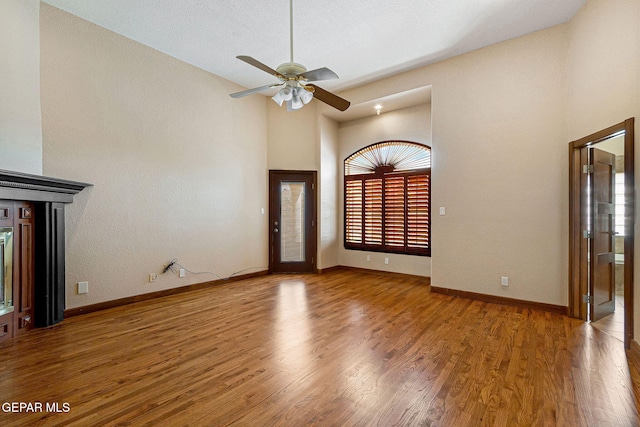 entryway with ceiling fan, wood-type flooring, and a high ceiling