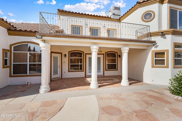 entrance to property with a porch, a balcony, and cooling unit