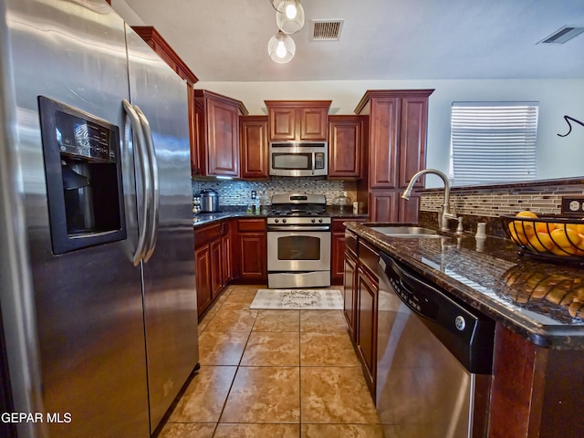 12298 Stansbury Dr, El Paso, TX 79928 - kitchen featuring tasteful backsplash, dark stone counters, stainless steel appliances, sink, and light tile patterned floors