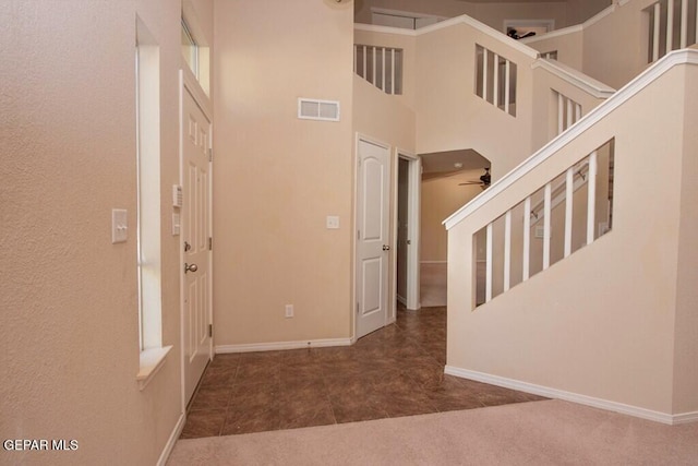 foyer entrance with a towering ceiling and ceiling fan