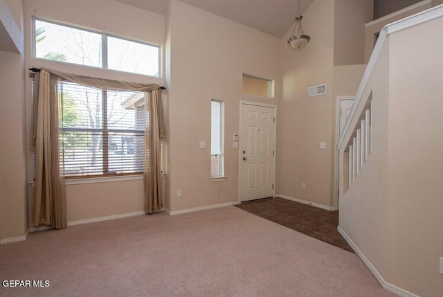 entryway with dark carpet and a high ceiling