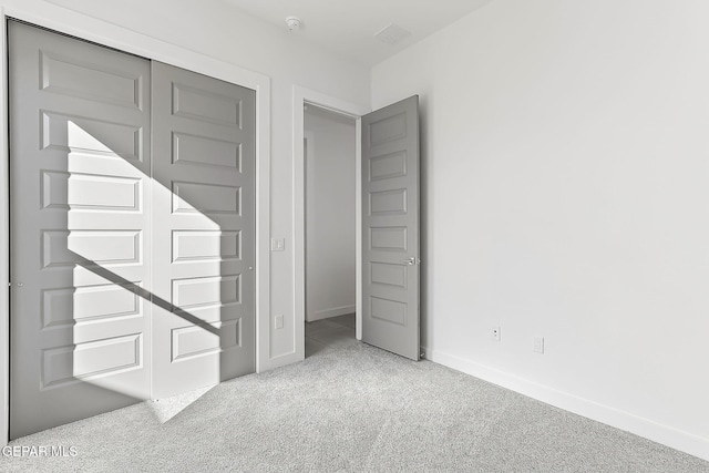 unfurnished bedroom with light colored carpet and a closet