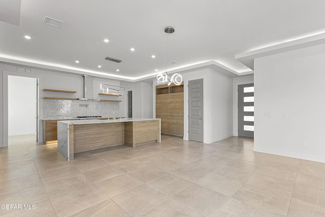 kitchen featuring tasteful backsplash, light tile patterned flooring, a spacious island, and decorative light fixtures