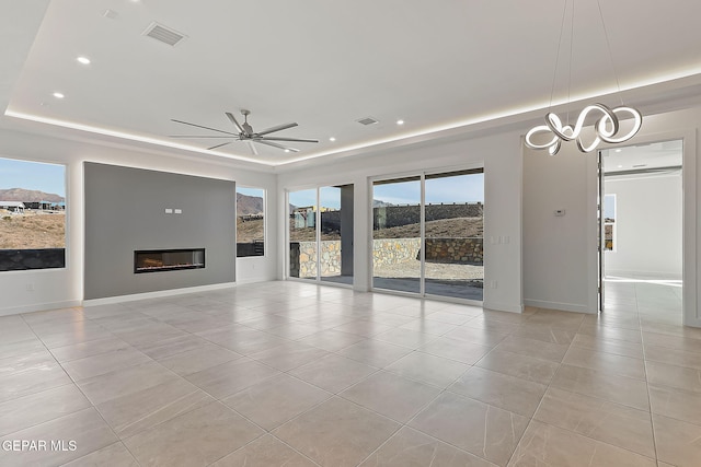 unfurnished living room with a tray ceiling, ceiling fan, and light tile patterned floors