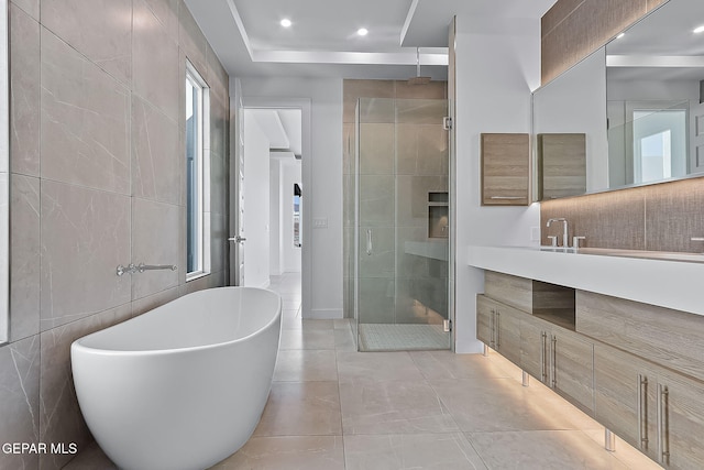 bathroom with plus walk in shower, vanity, tile walls, and tile patterned flooring