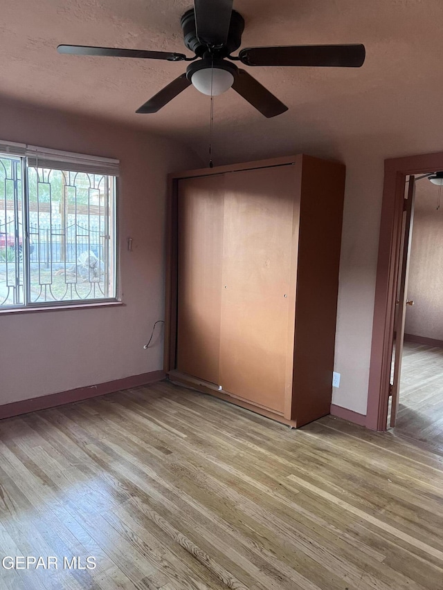 unfurnished bedroom with a textured ceiling, light hardwood / wood-style floors, a closet, and ceiling fan