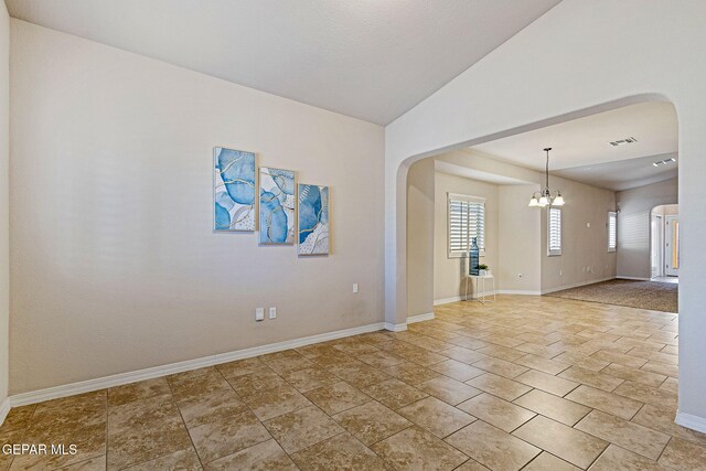 empty room with a chandelier and vaulted ceiling