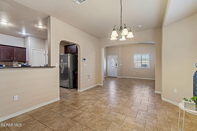 kitchen with pendant lighting, a notable chandelier, dark brown cabinets, and stainless steel fridge with ice dispenser