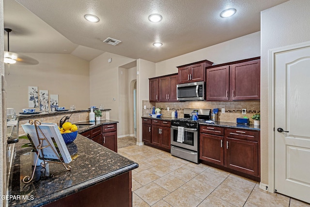 kitchen featuring sink, tasteful backsplash, lofted ceiling, light tile patterned floors, and appliances with stainless steel finishes