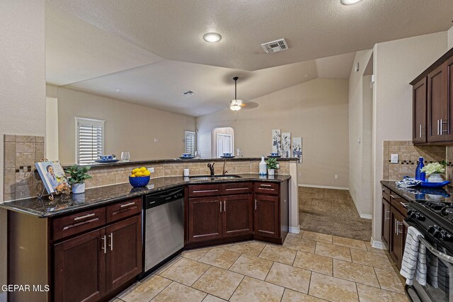 kitchen featuring lofted ceiling, dark stone counters, ceiling fan, kitchen peninsula, and stainless steel appliances