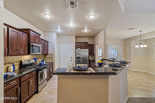 kitchen featuring a textured ceiling, a center island, stainless steel appliances, and an inviting chandelier