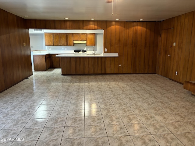 kitchen featuring wood walls, sink, backsplash, stove, and kitchen peninsula