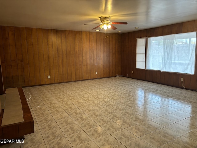 empty room with ceiling fan and wooden walls