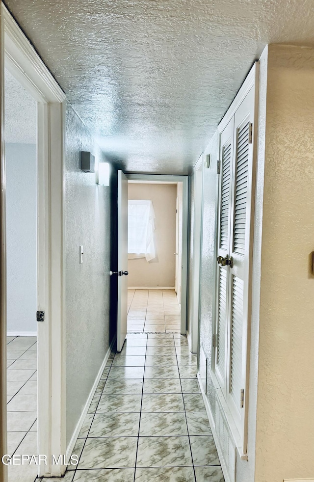 hall featuring light tile patterned floors and a textured ceiling